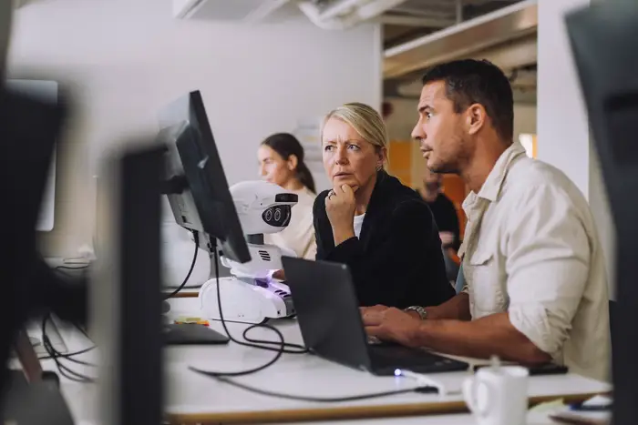 Photo of Employees Discussing Work While Looking at a Screen